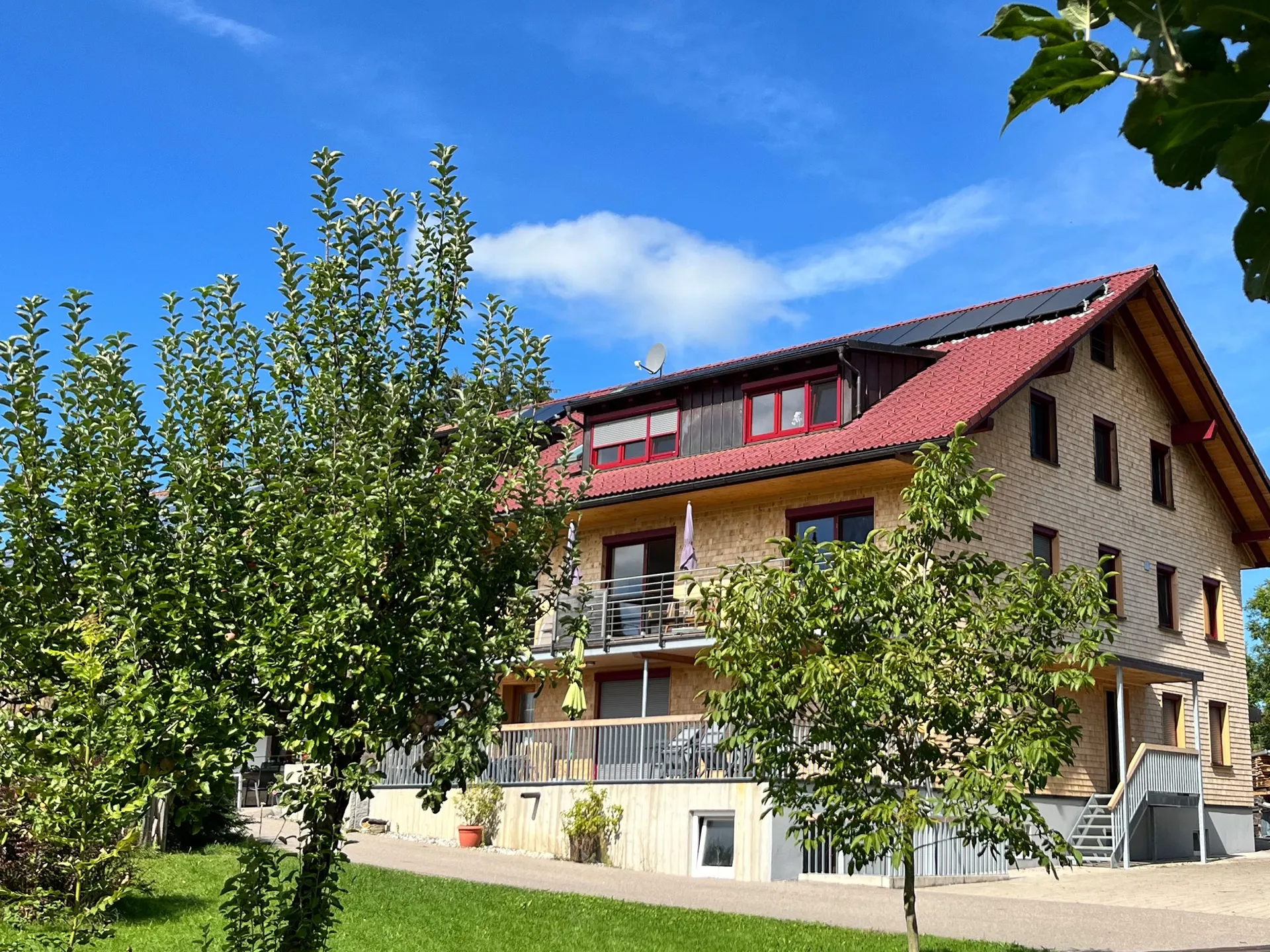 Das Haus vom Ferienhof Fink mit Balkonen und Obstbäumen unter blauem Himmel