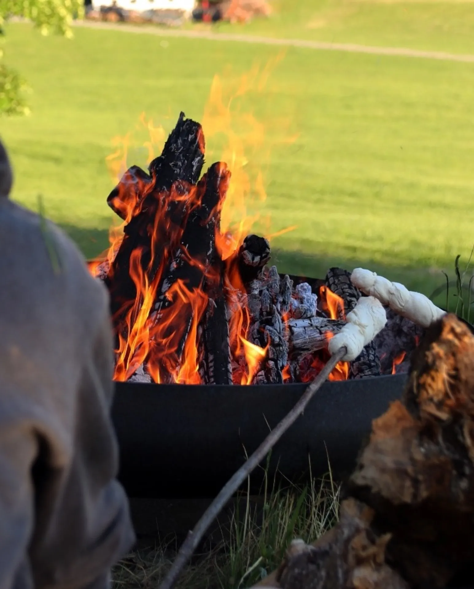 Kinder backen Stockbrot am Feuer